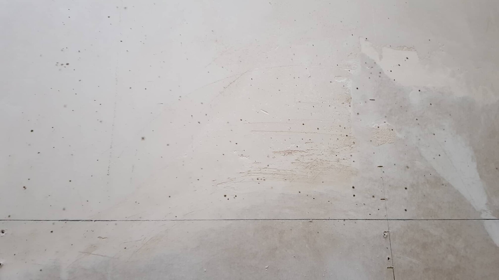 Unbearbeiteter Betonboden im Rohbau mit Fugen und kleinen Flecken