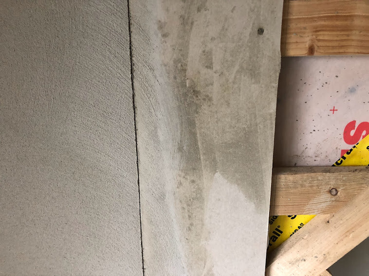 Nahaufnahme einer Betonwand neben Holzrahmenbau mit gelbem Sicherheitsband.