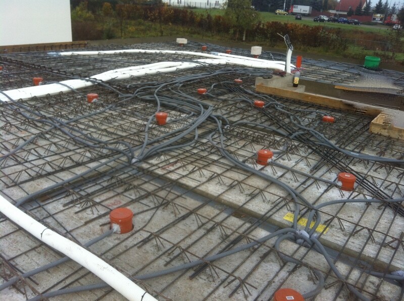 Rohbau: Bewehrung und Installationen auf einer Betonbodenplatte sichtbar
