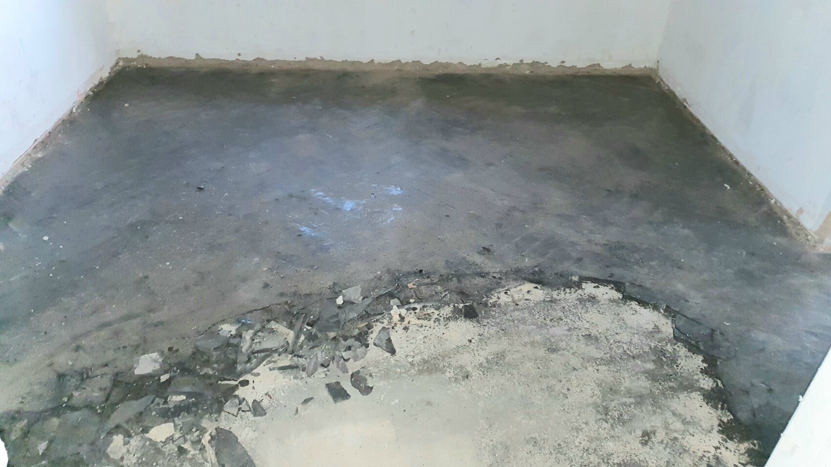 Leeres Zimmer mit rohem Betonboden; Vordergrund mit Schutt und Abbruchresten.