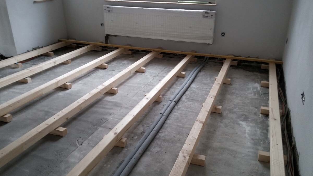Innenraum mit Holzbodenbalkenrahmen auf Betonboden, Heizkörper an der Wand