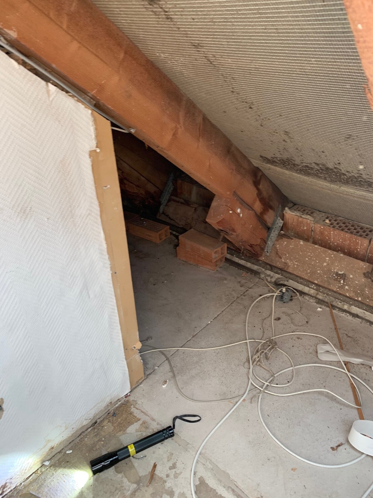Dachboden mit Holzbalken, Dämmung und Kabeln im offenen Rohbauzustand