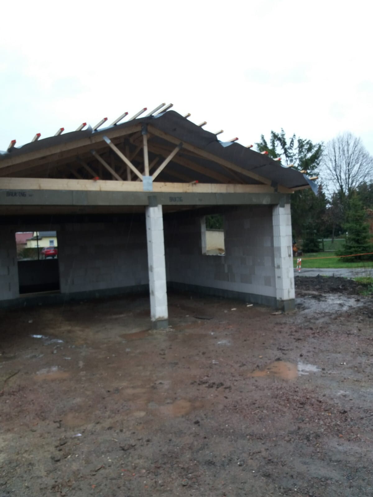 Unfertiges Gebäude mit Satteldach, sichtbare Dachstuhlkonstruktion aus Holz, Matschboden.