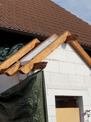 Rohbau: Dachkonstruktion mit Holztraeger ueber einer Hausfassade