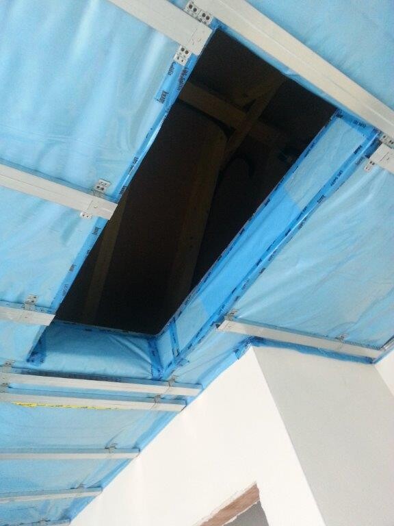 Offene Dachöffnung mit blauer Baufolie an einer Rohbaudecke, Baustelle sichtbar.