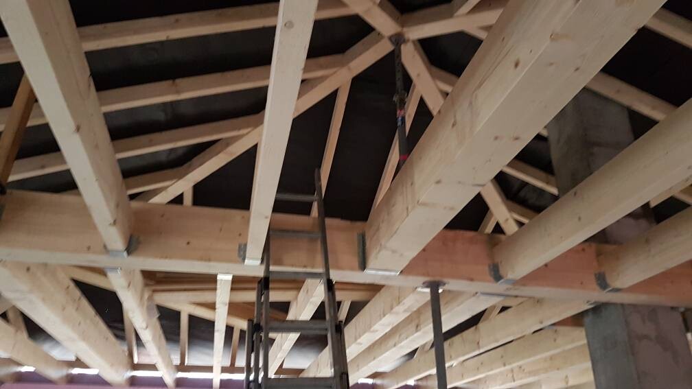Dachstuhl aus Holzbalken mit einer Leiter im Rohbau.