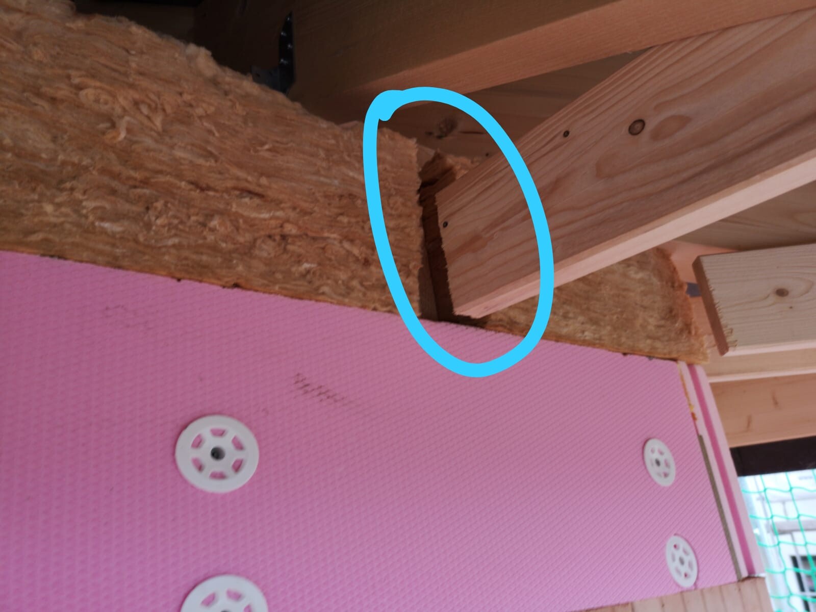 Innenansicht einer Baustelle: Holzbalken, Dämmung und sichtbare Nut-Verbindung