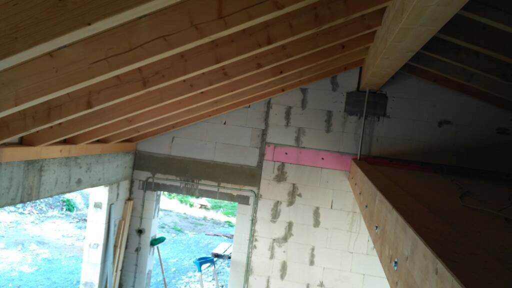 Rohbau Innenraum mit sichtbarem Dachstuhl, unverputzten Betonwänden und Bauwerkzeugen