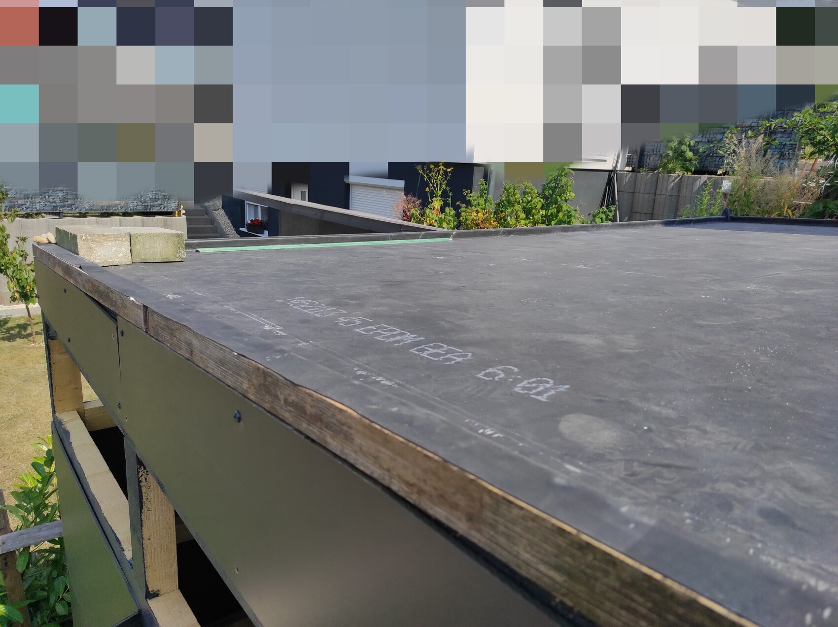 Flache Dachterrasse auf Baustelle mit Holzrahmen und Gebäuden im Hintergrund