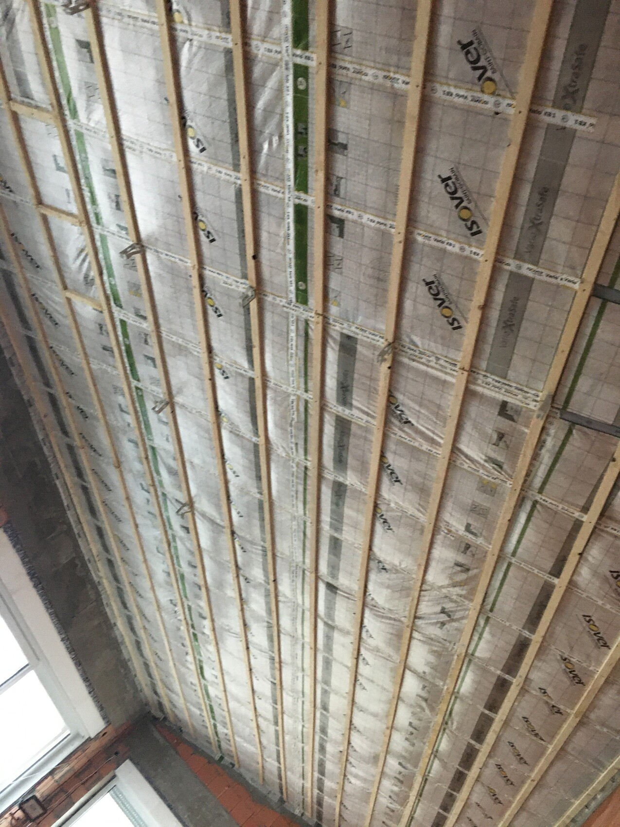Freigelegtes Holzständerwerk mit Dämmstoff-Dämmung im Deckenbereich eines Bauprojekts.