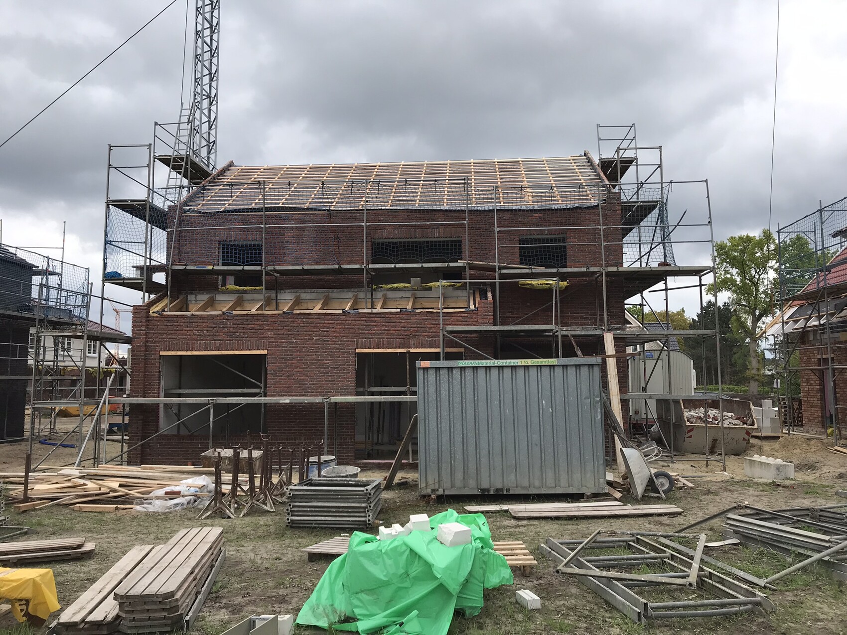 Rohbau eines zweigeschossigen Ziegelhauses mit Gerüst auf einer Baustelle.