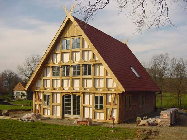 Rohbau eines Fachwerkhauses mit rotem Dach und sichtbarer Holzkonstruktion