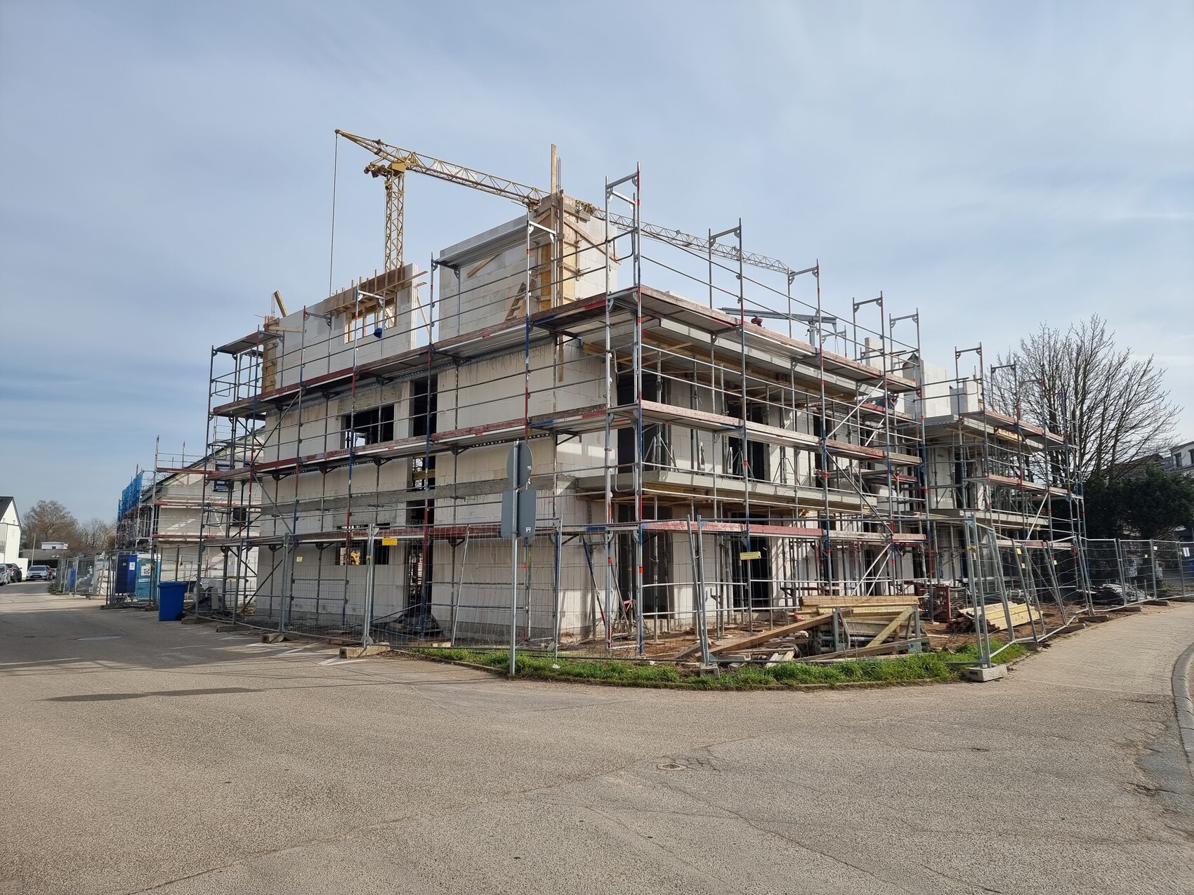 Mehrstöckiges Bauprojekt mit Gerüst, Kran und Baumaterialien auf einer Baustelle.