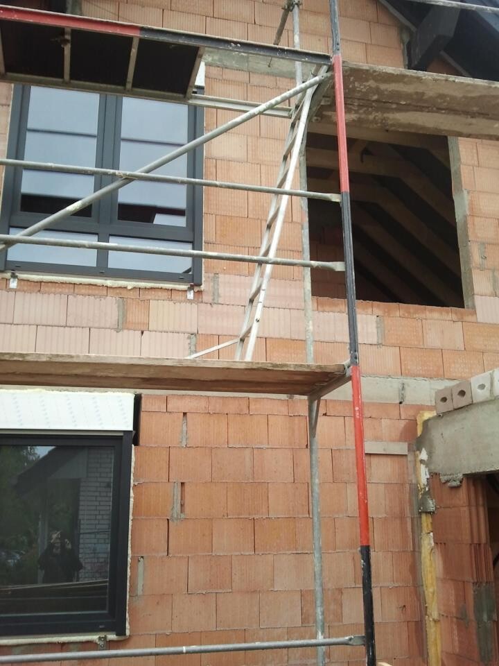 Rohbau aus Ziegeln mit Baugerüst, Fensterrahmen und offener Wandöffnung.