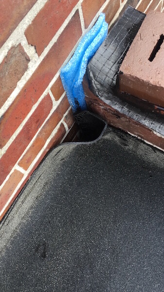 Rohbau-Fassade: Ziegelwand, schwarzer Untergrund und blaues Dichtband an der Ecke