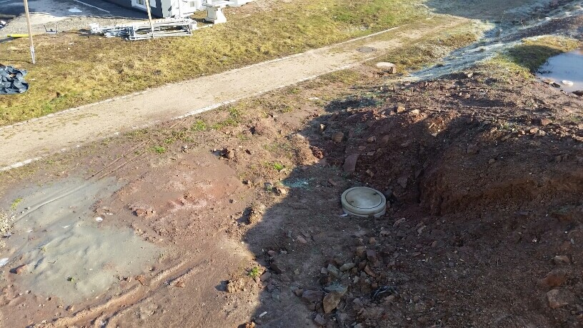 Baustelle mit Baugrube und runder Abdeckung im Boden, Erdaushub sichtbar