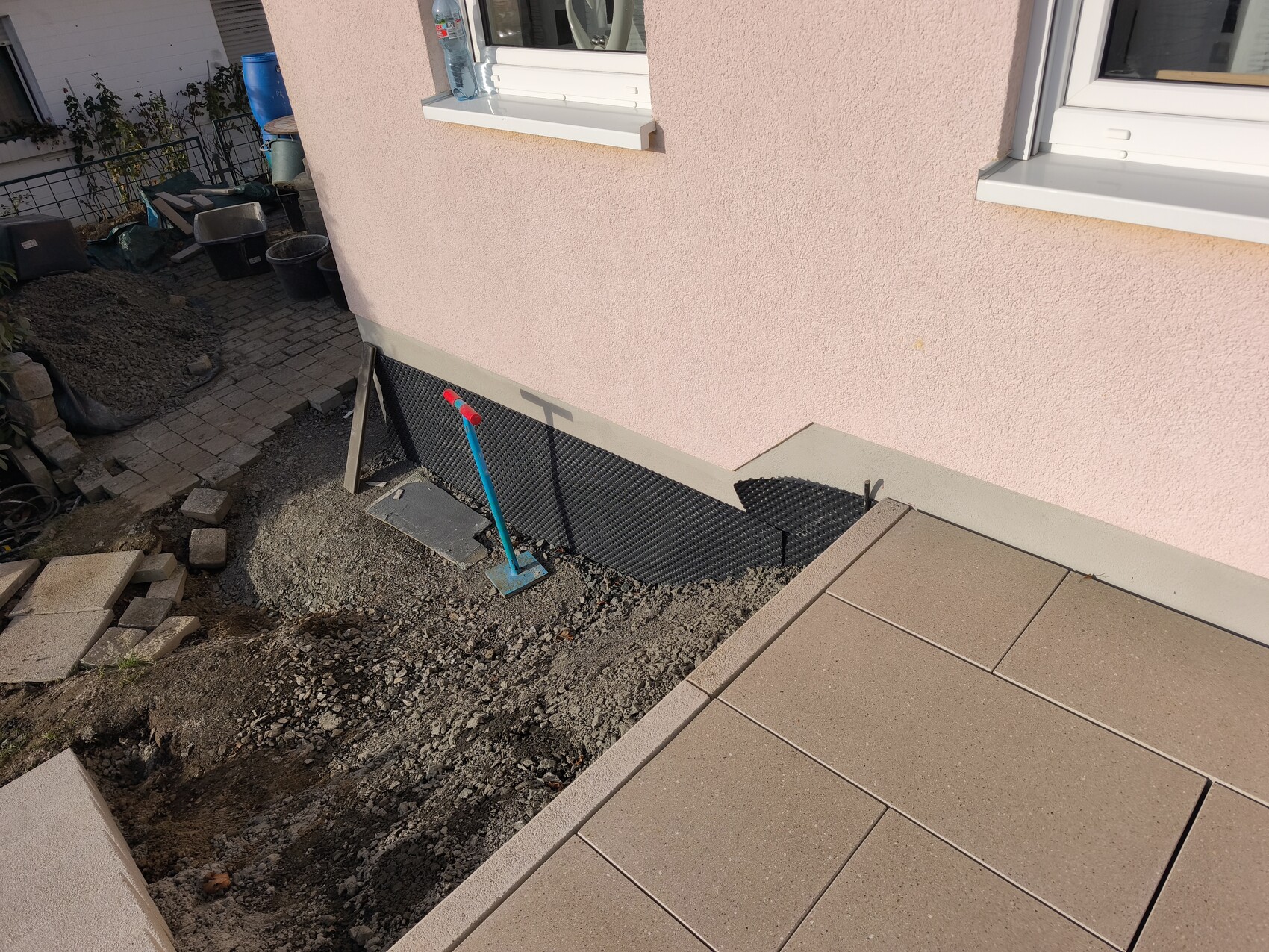 Außenansicht eines Hauses mit Fundamentdämmung, Kies und Bauwerkzeugen im Außenbereich