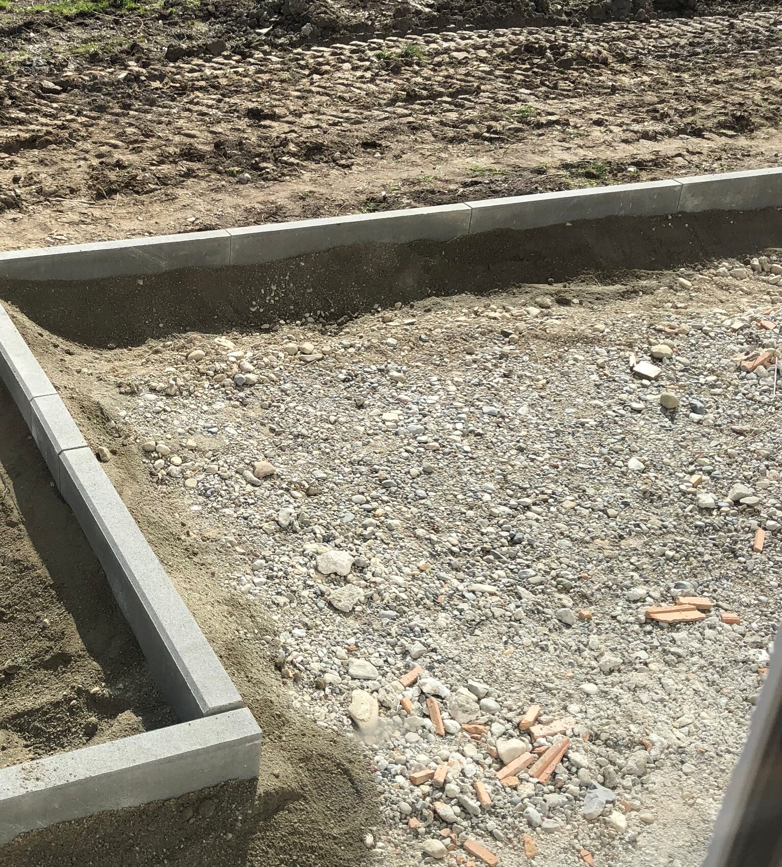 Baustelle mit Betonfundament-Wänden, Kies und Steinen in einer Baugrube