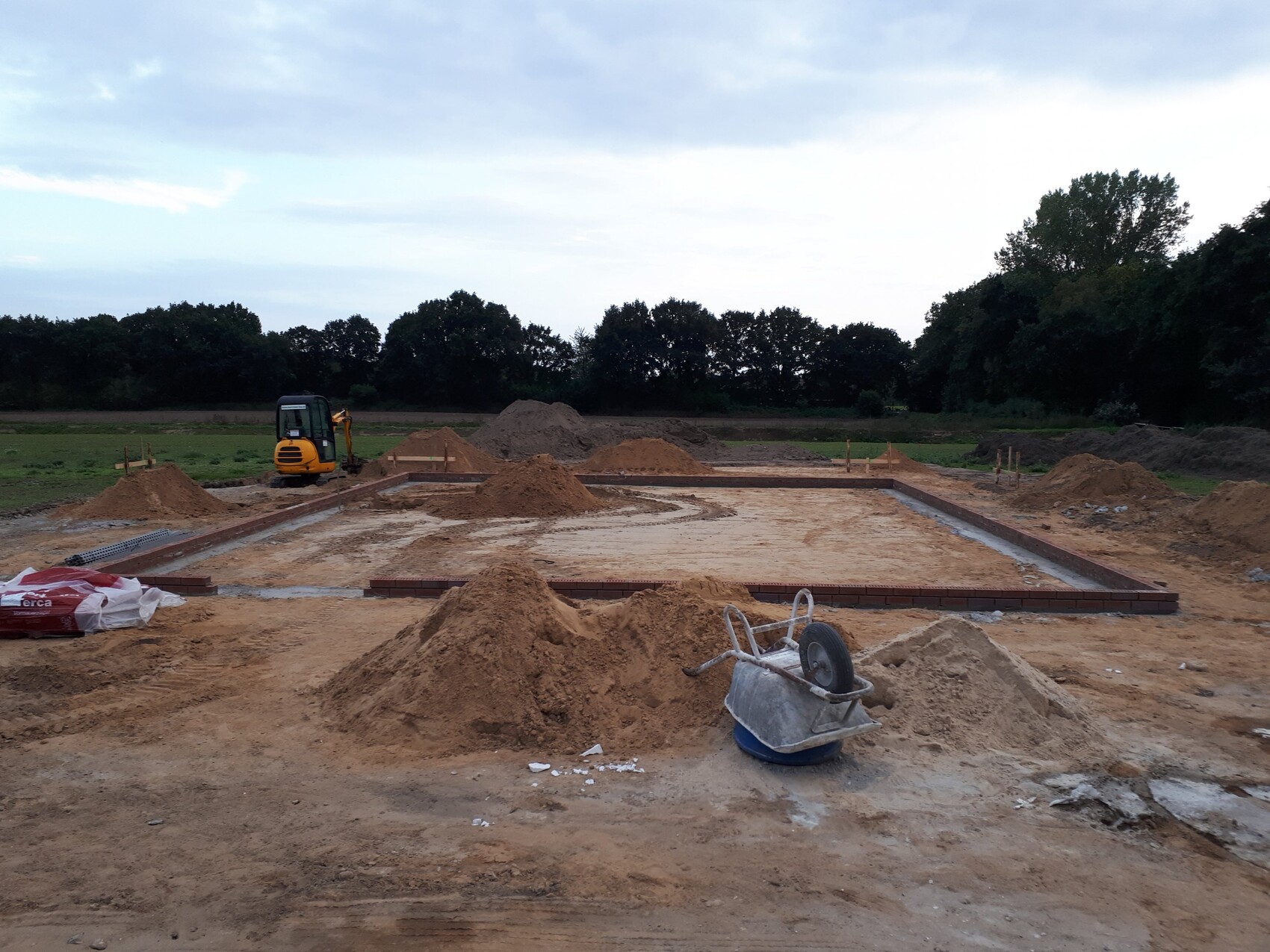 Baustelle mit Fundamentrahmen, Erdarbeiten und Kleingerät auf einer Baufläche