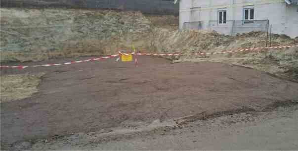 Baustelle mit freigelegtem Erdreich, Absperrband und Haus-Rohbaufundament