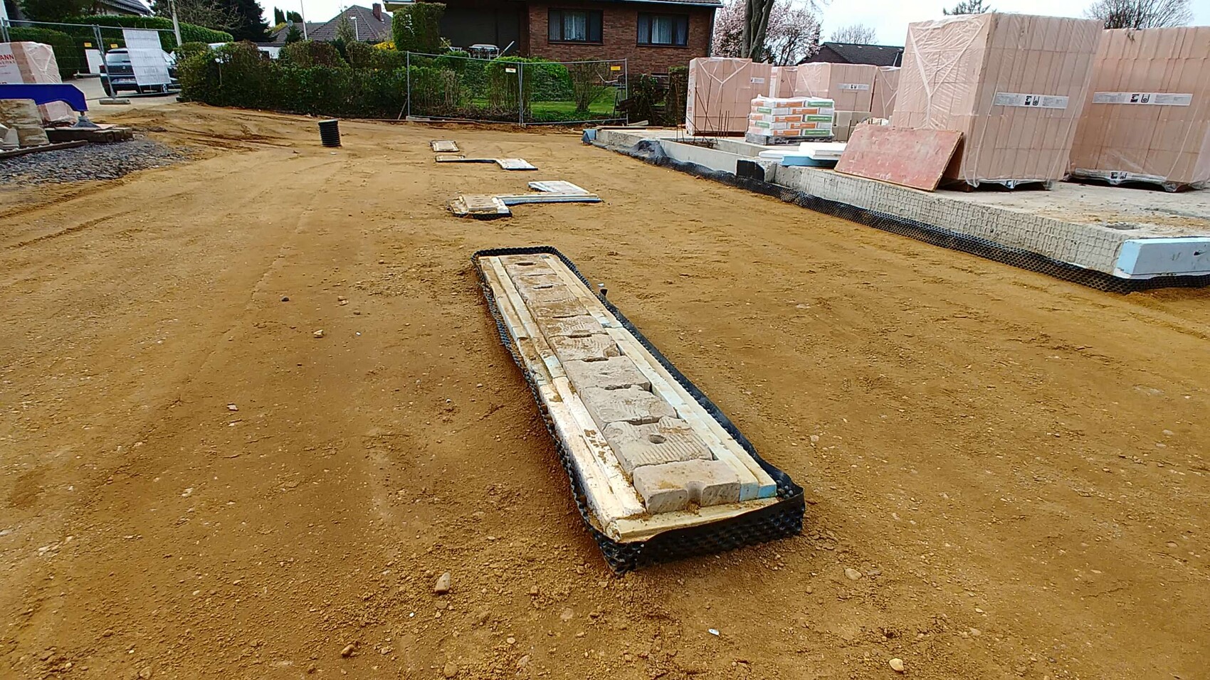 Baustelle mit Fundamentformen, Baumaterialien und Erdaushub auf Baugrundstück