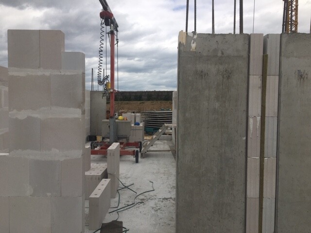 Baustelle mit Betonblöcken, fertigen Betonwänden und Baugeräten im Aufbau
