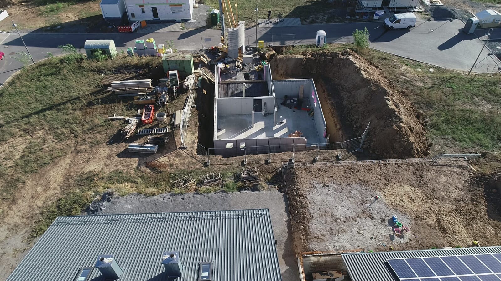 Luftaufnahme einer Baustelle mit Fundamentwänden und Erdaushub im Rohbau