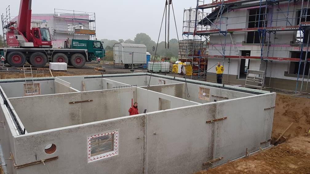 Kellerfundament aus Beton auf Baustelle, Kran, Gerüst, Bauarbeiter