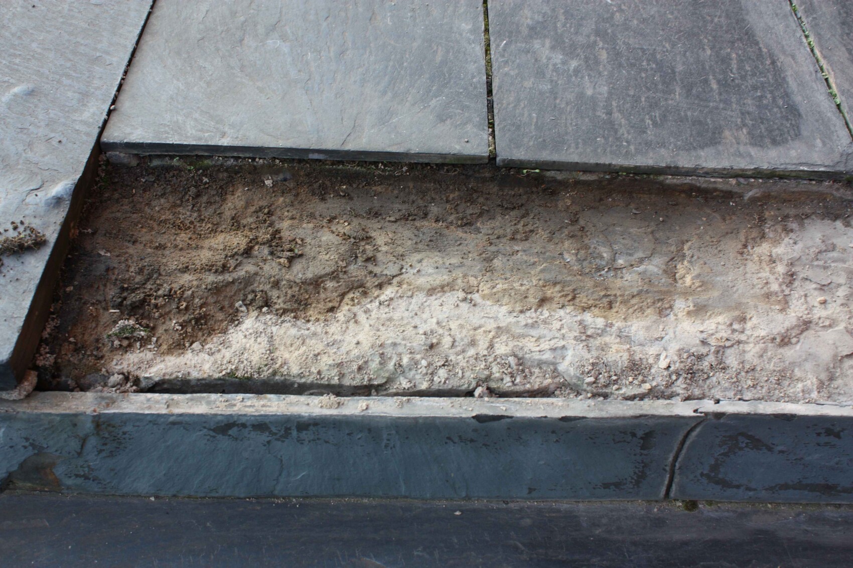 Nahaufnahme von Betonplatten und Erdreich auf einer Baustelle, Fundamentarbeiten