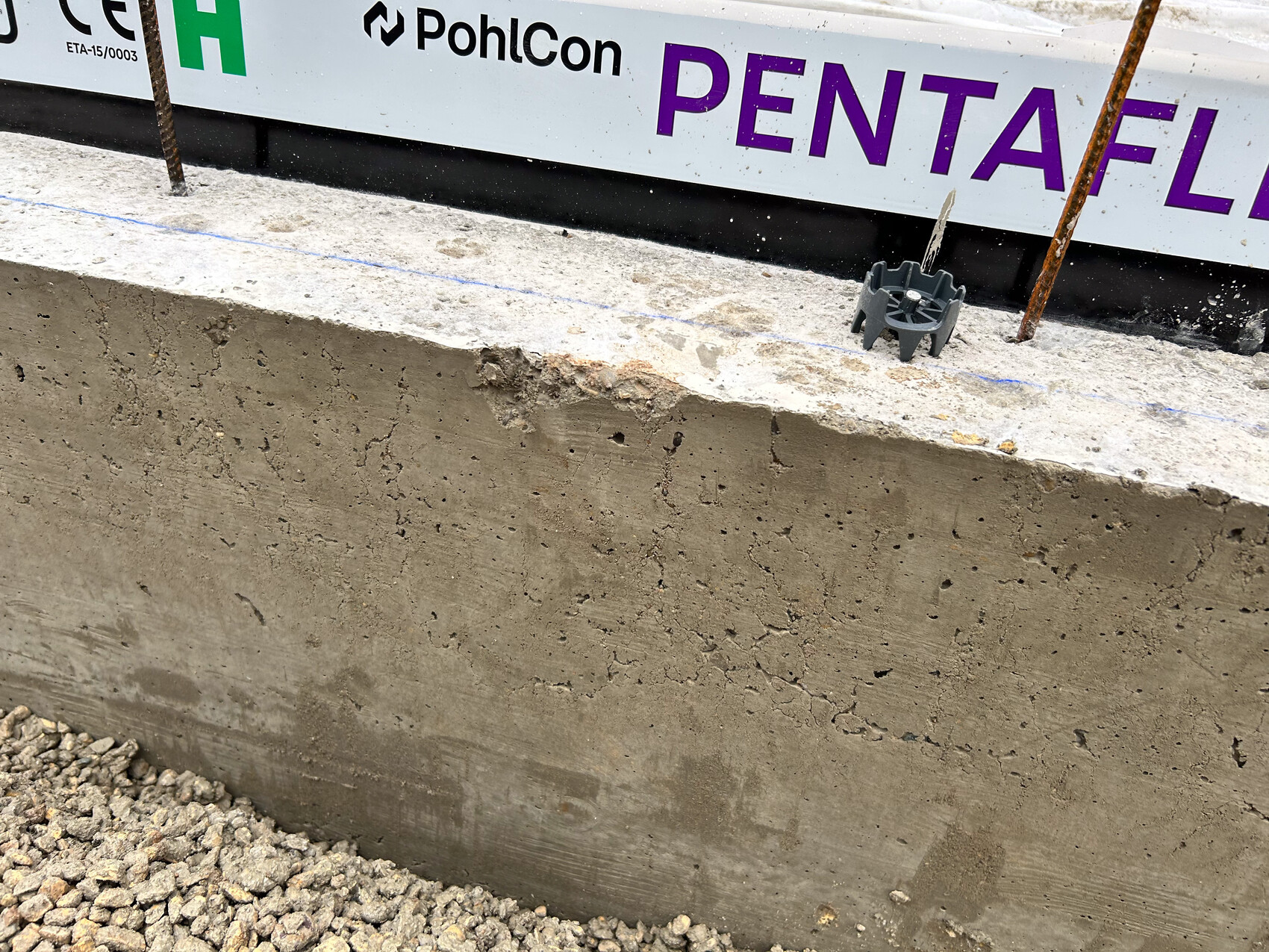 Betonfundament mit Bewehrung auf einer Baustelle im Hintergrund