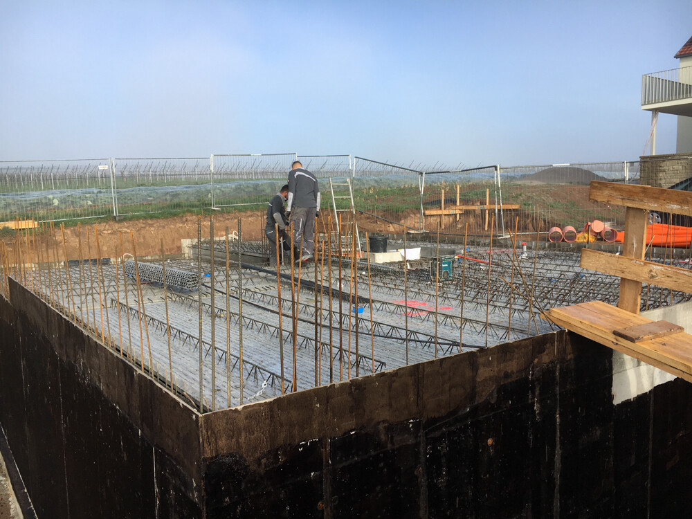 Bauarbeiter arbeiten auf einer Fundamentplatte mit Bewehrung aus Stahlstangen; Baustelle im Freien