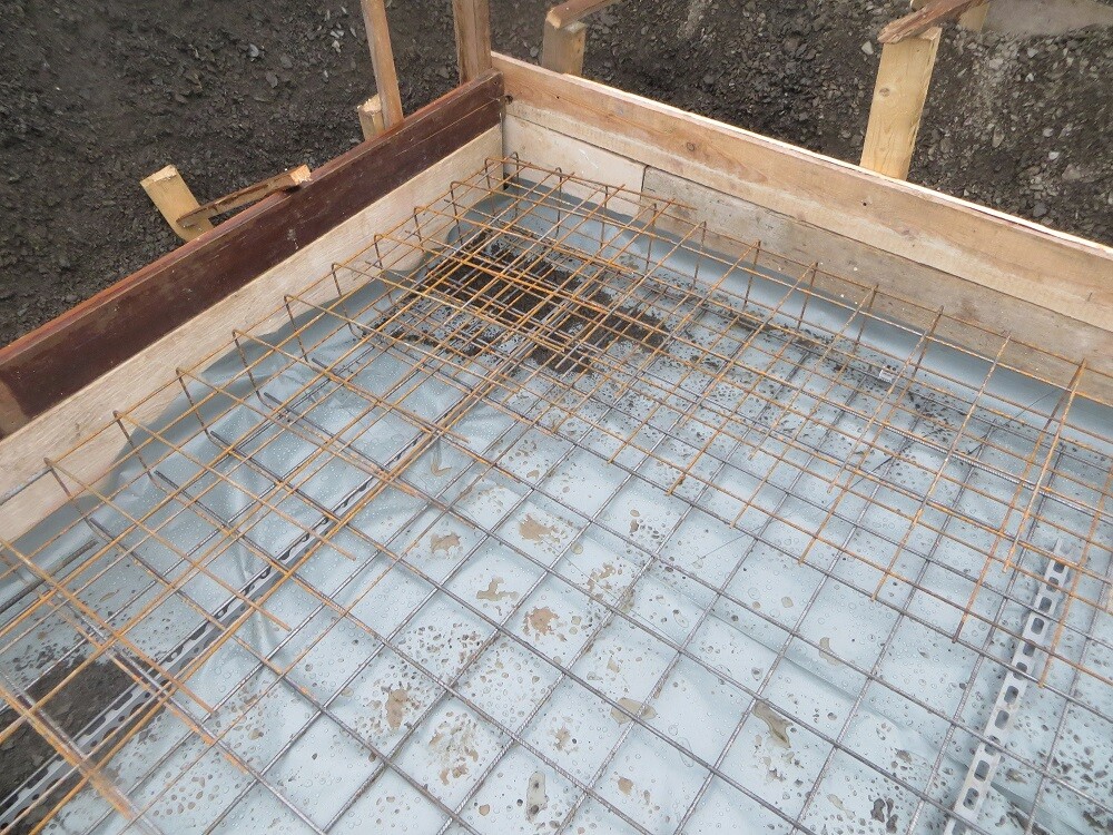 Stahlarmierungsgitter liegt auf einer vorbereiteten Betonfundamentform im Rohbau.