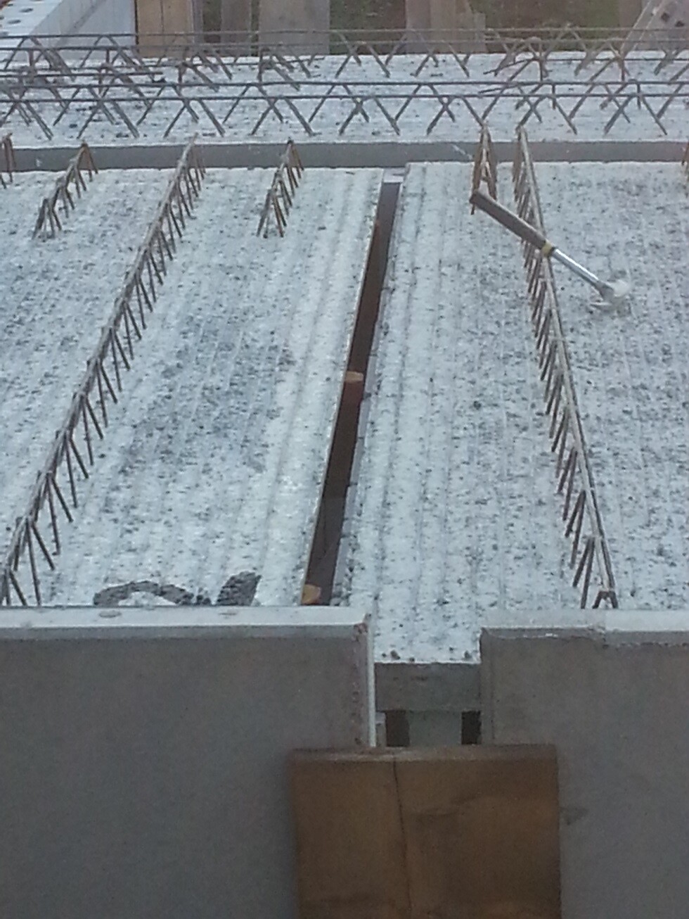 Betonfundament mit Bewehrung aus Stahlstangen auf einer Baustelle, Blick von oben