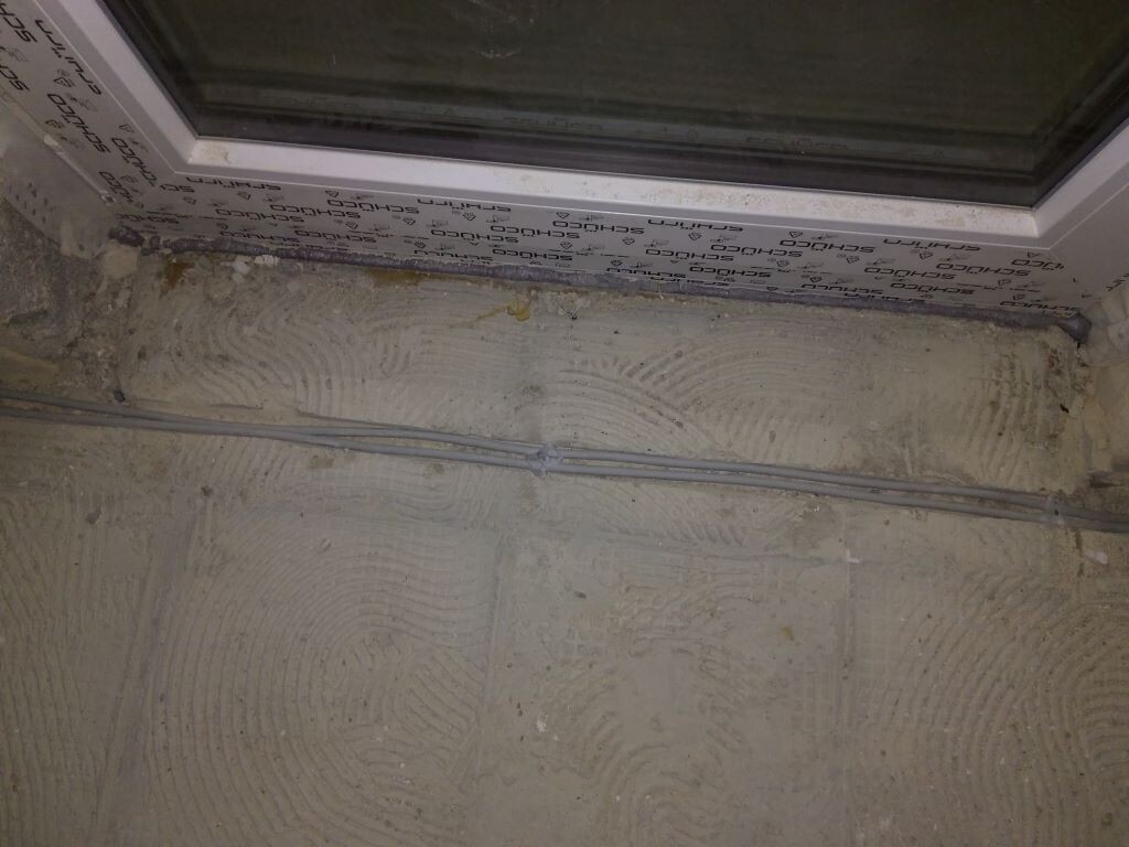 Fensterrahmen mit Schutzfolie, Rohbetonboden mit Trowel-Muster, Kabel verlegt