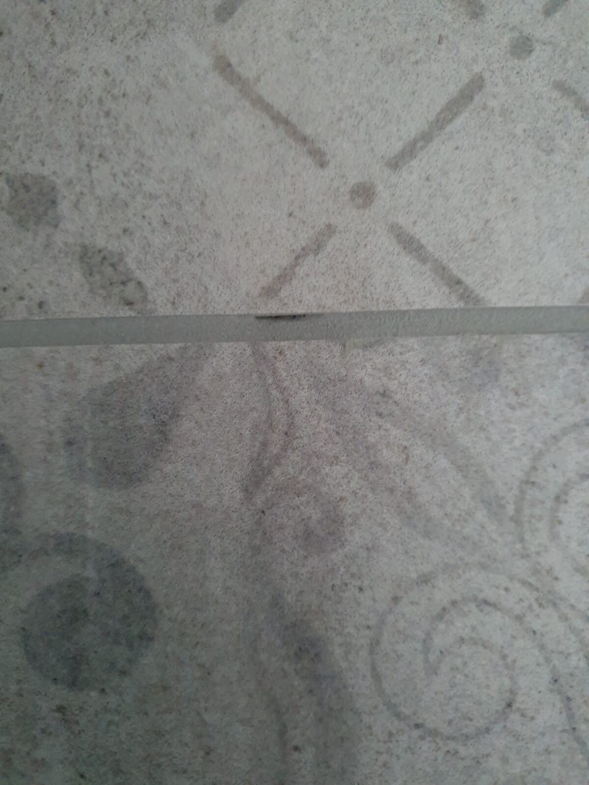 Graue Betonoberfläche mit feiner Struktur, horizontaler Streifen und X-Markierungen.
