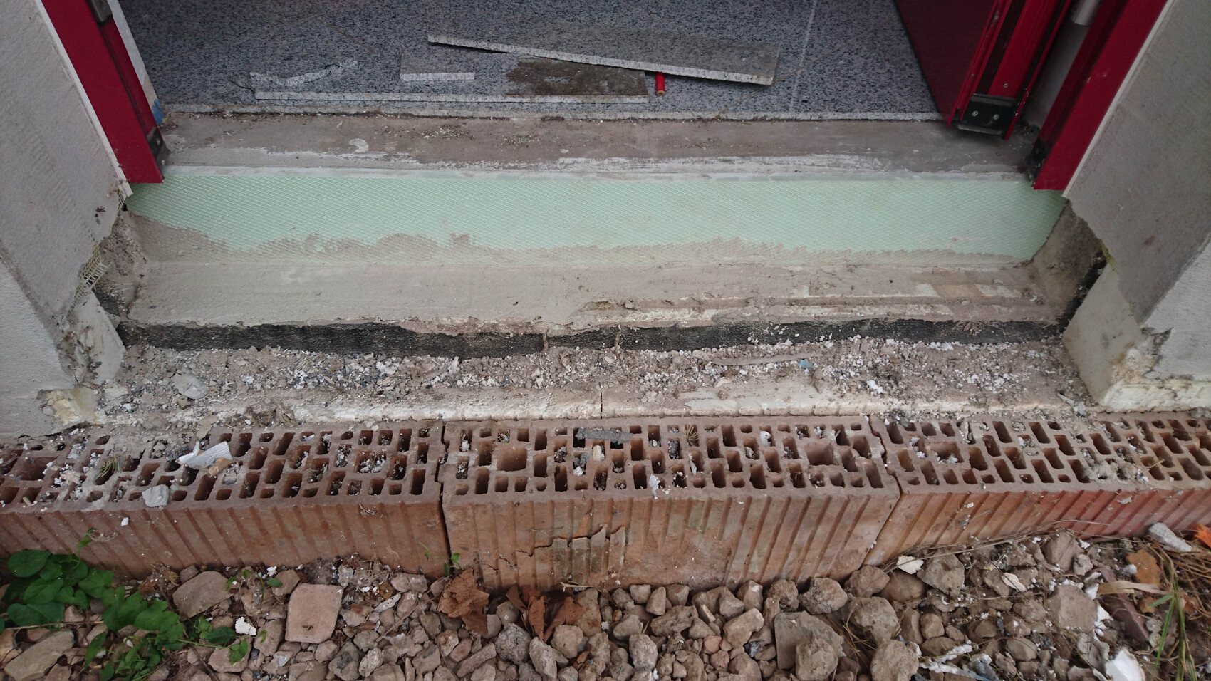 Unfertiger Rohbau-Eingang mit Fundament, Bruchsteinen und Bauabfällen
