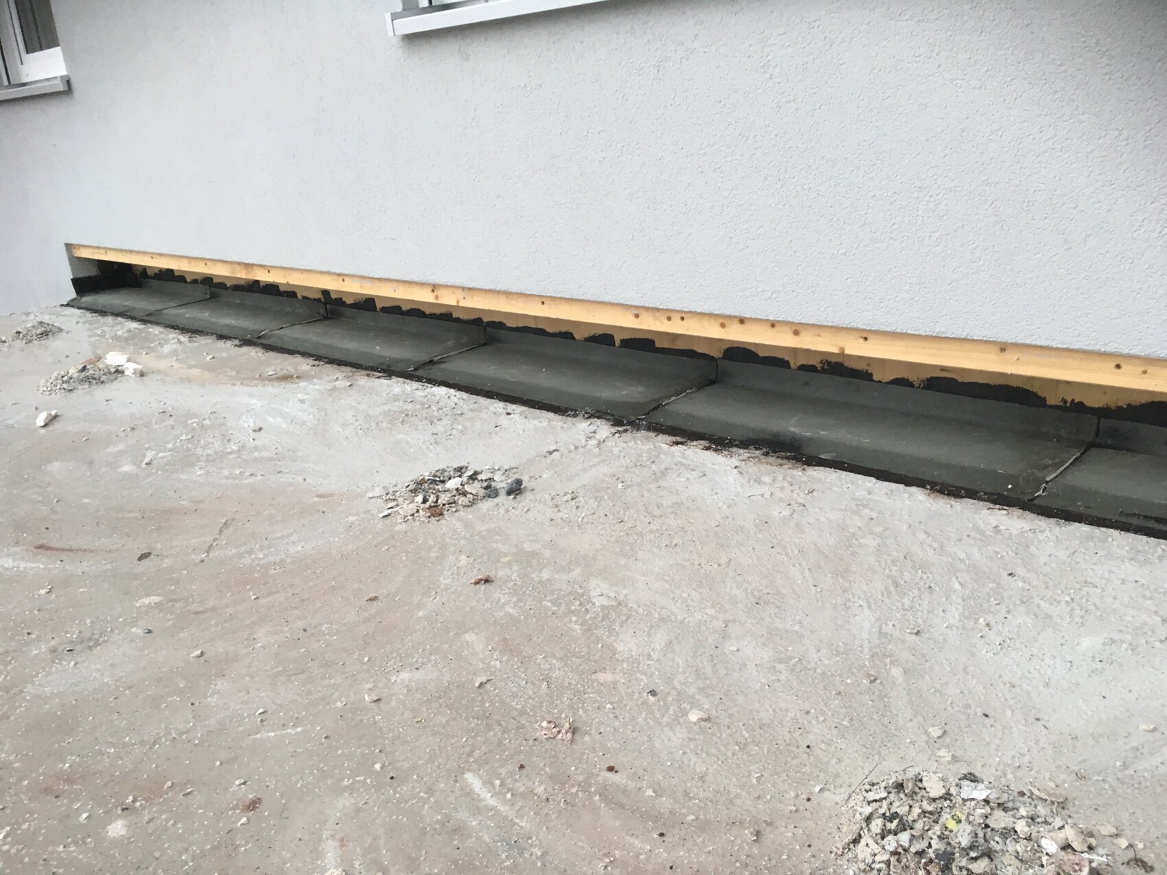 Außenwand im Rohbau mit Holzleiste und Abdichtung am Fundament