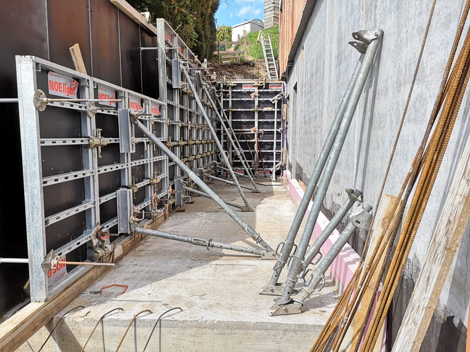 Baustelle mit Metallformrahmen, Stützen und Bewehrungsstahl an Betonwand