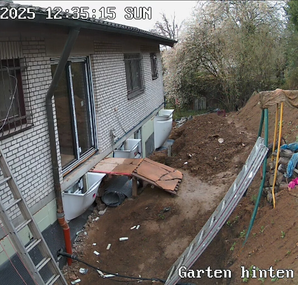 Außenbereich eines Hauses im Rohbau mit Erdarbeiten, Fundamenten und Gartenvorbereitung.