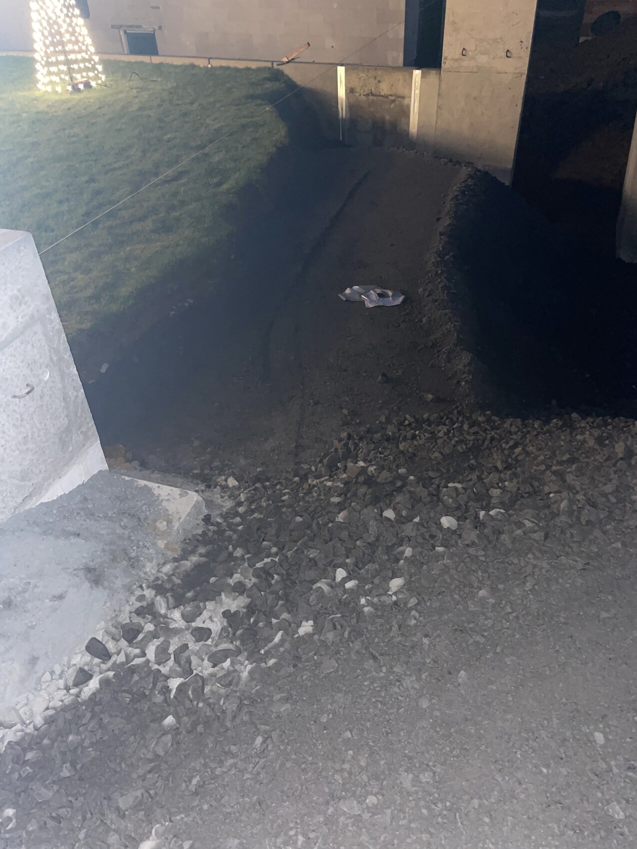 Baugrube mit Kies, Erdmassen und Betonfundamenten an einer Baustelle