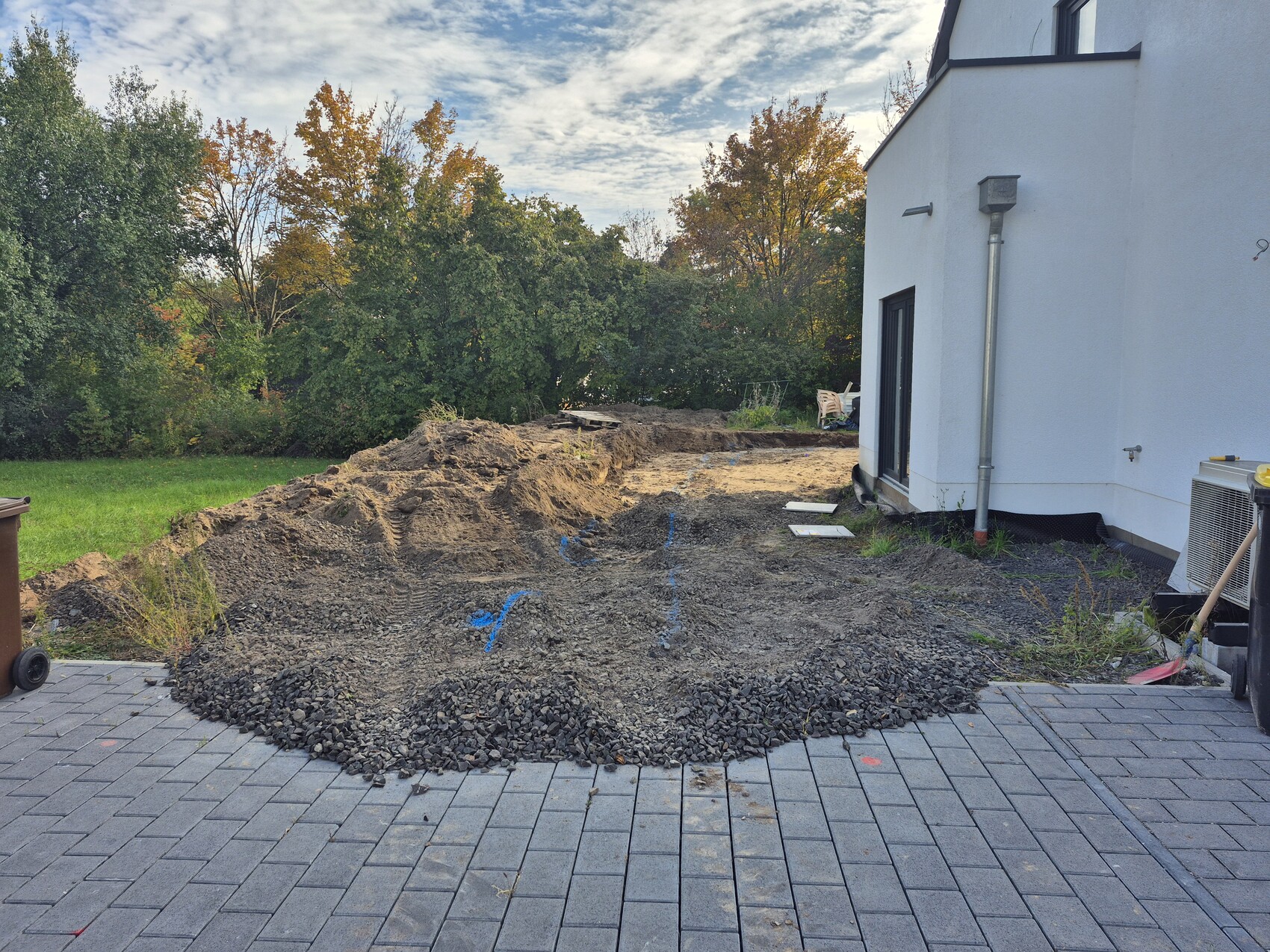 Grubenaushub im Hof neben weißem Haus, vorbereitendes Fundament