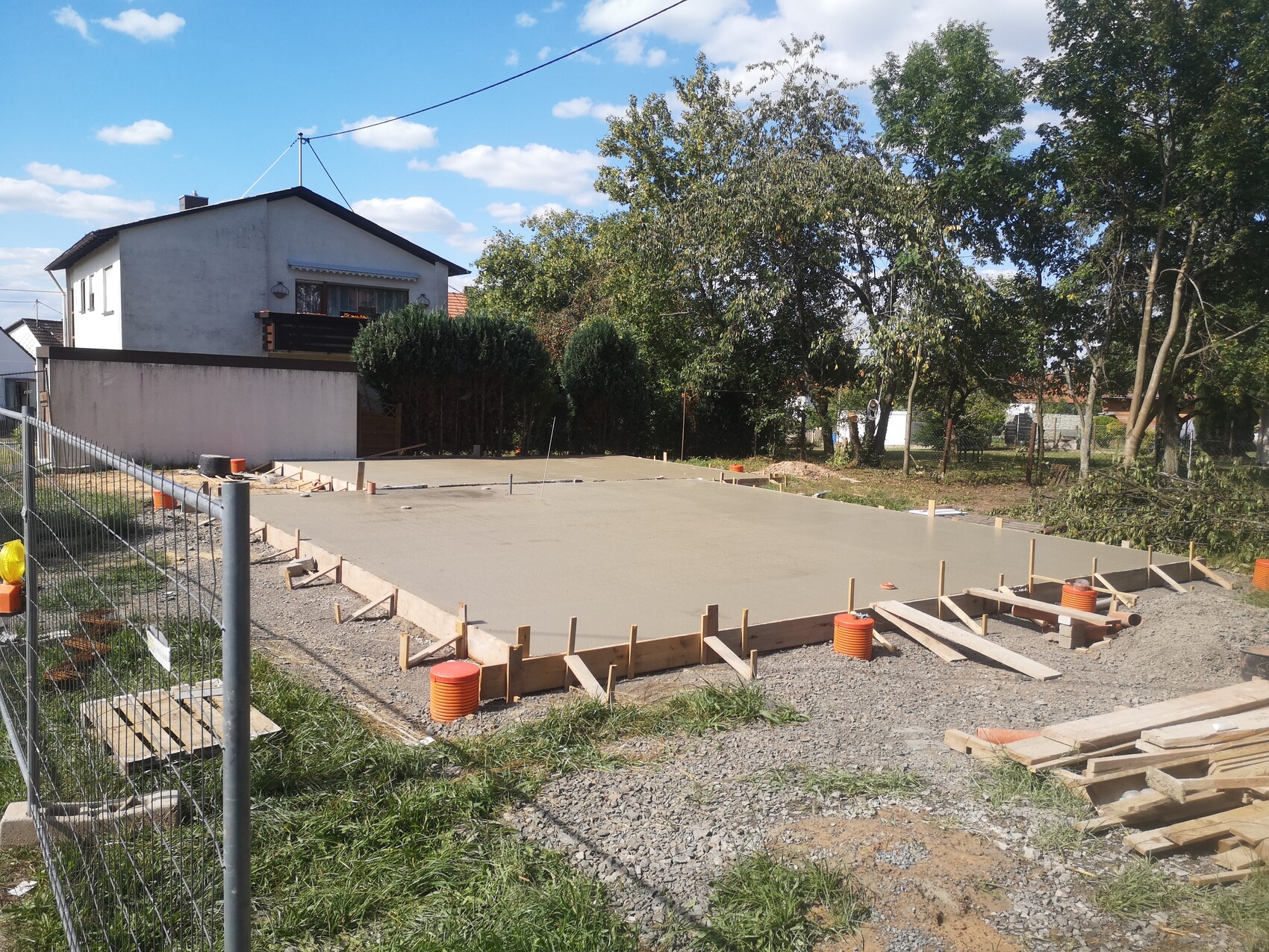 Frisch gegossene Fundamentplatte mit Holzformwerk, Baustellenumgebung am Haus.