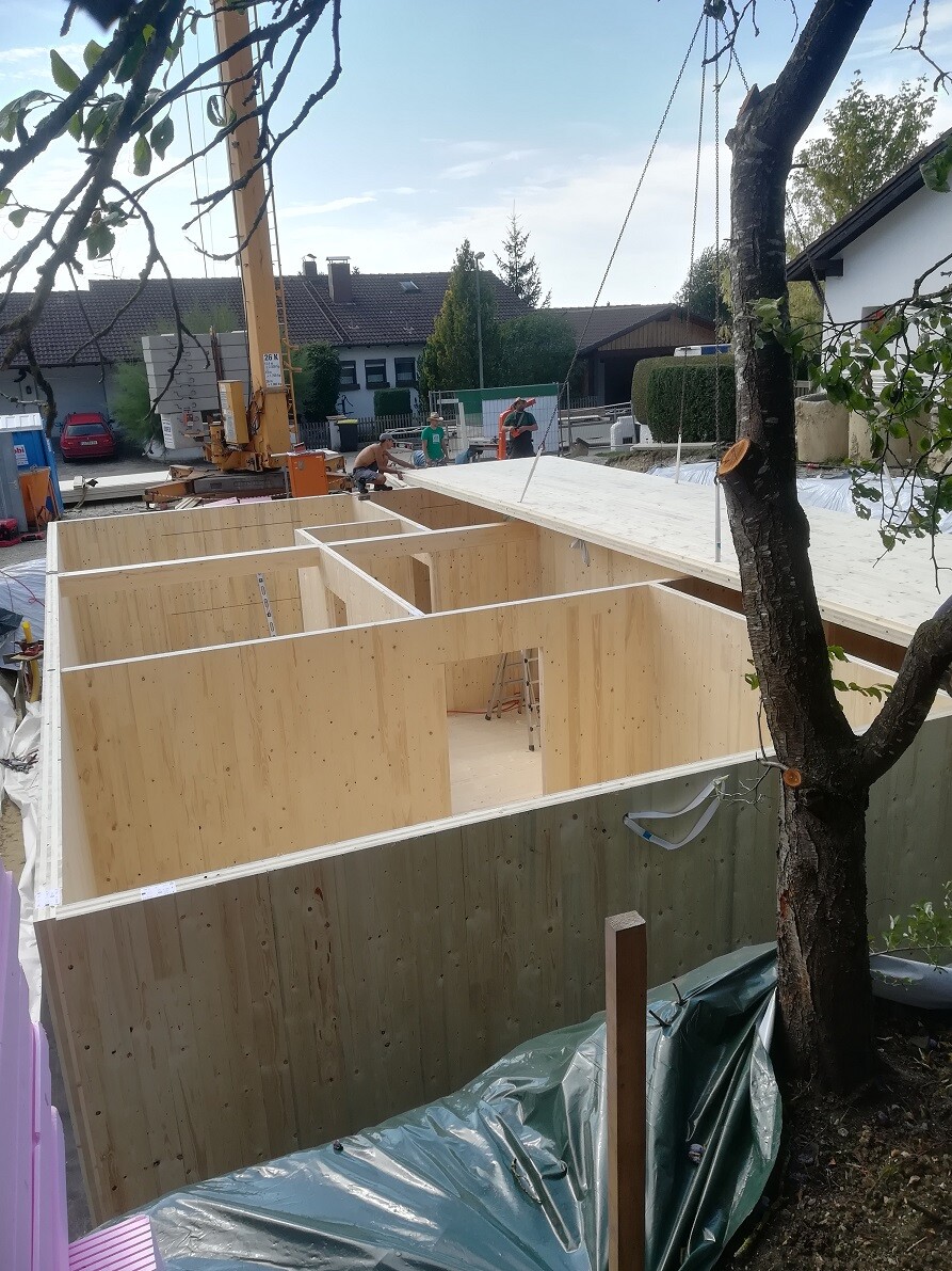 Baustelle: Holzrahmen-Haus im Bau, Arbeiter arbeiten, Kran im Hintergrund.
