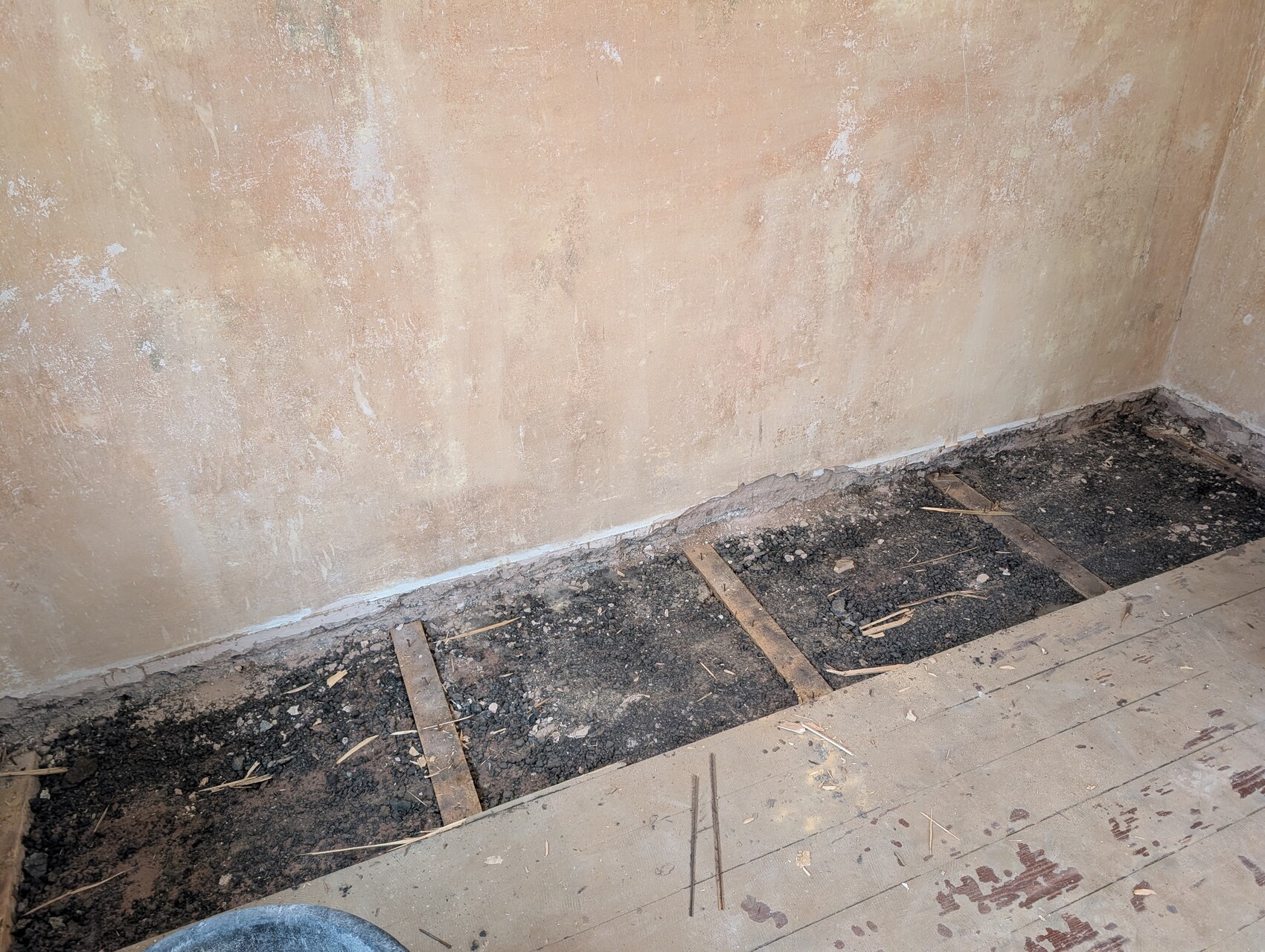 Raum mit offener Baugrube am Boden, Erde, Holzbalken und Renovierungsarbeiten.