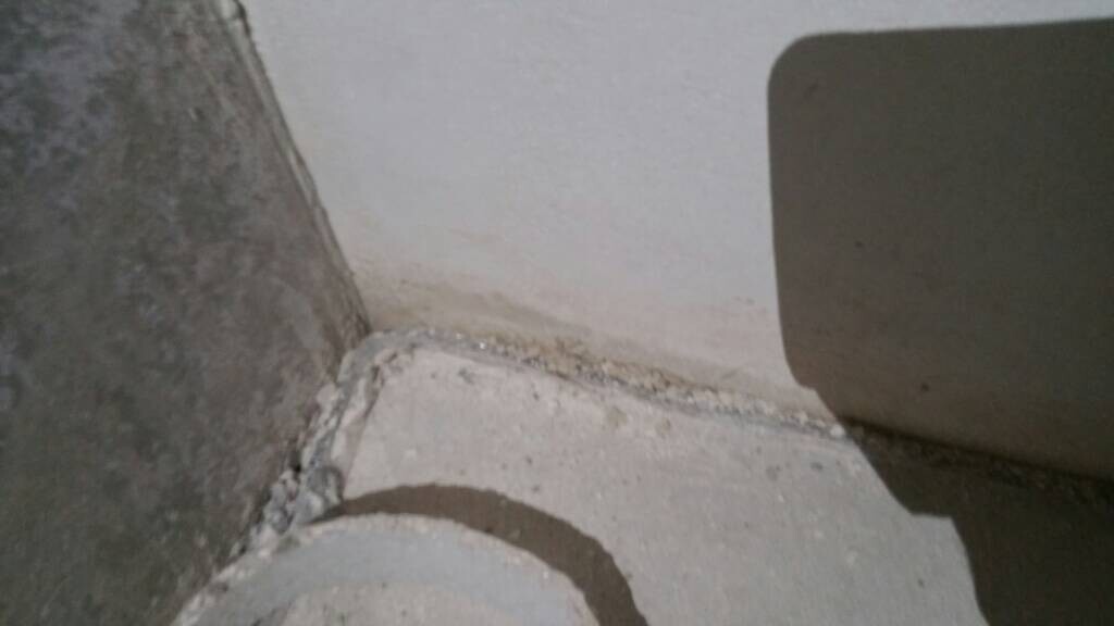 Ecke eines Rohbaus: unbehandelter Betonboden, Wand mit Sichtmauerwerk und Mörtelreste