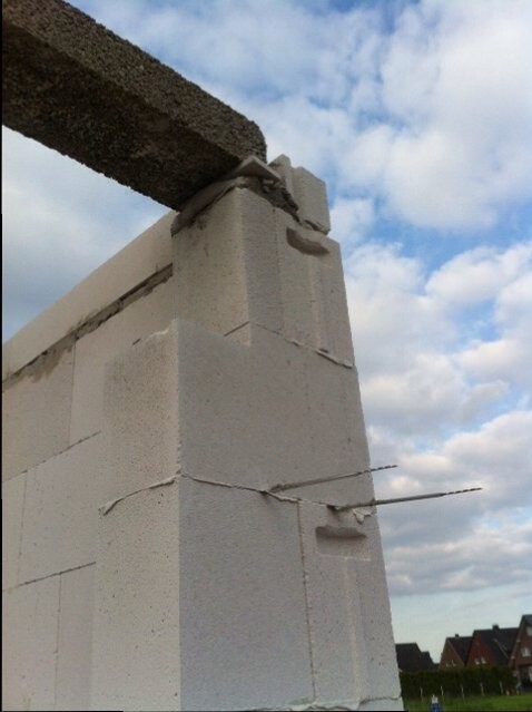 Nahaufnahme einer Betonblockwand im Rohbau mit Bewehrung