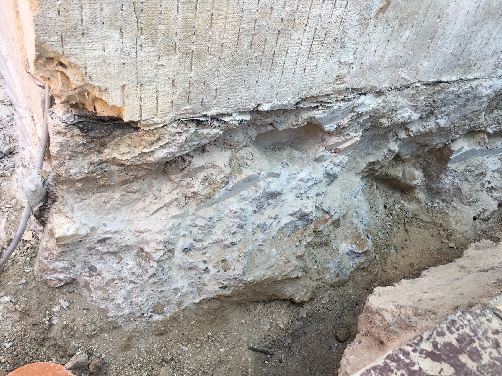 Außerhalb der Baugrube sichtbar offenes Fundament und Felsboden bei Rohbauarbeiten