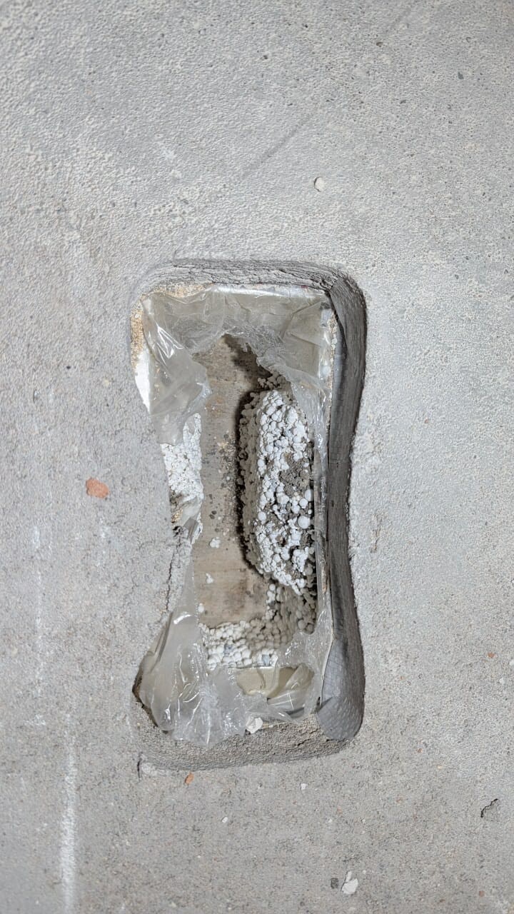 Offene Fundamentöffnung im Rohbaubeton mit Kies und Dichtungsmaterial