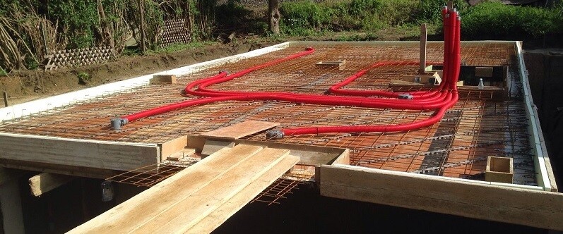 Fundamentbau mit Bewehrung, Holzformen und roten Kabelrohren.