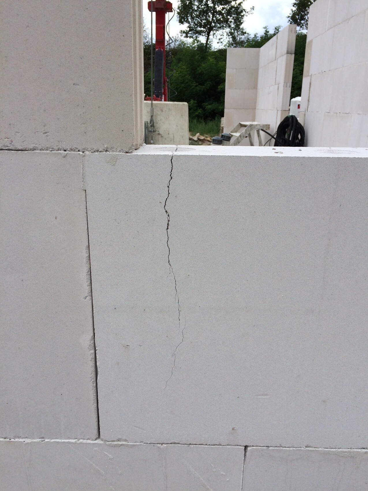 Baustelle mit Betonblöcken, Riss in der Wand und Bauwerkzeuge im Hintergrund.